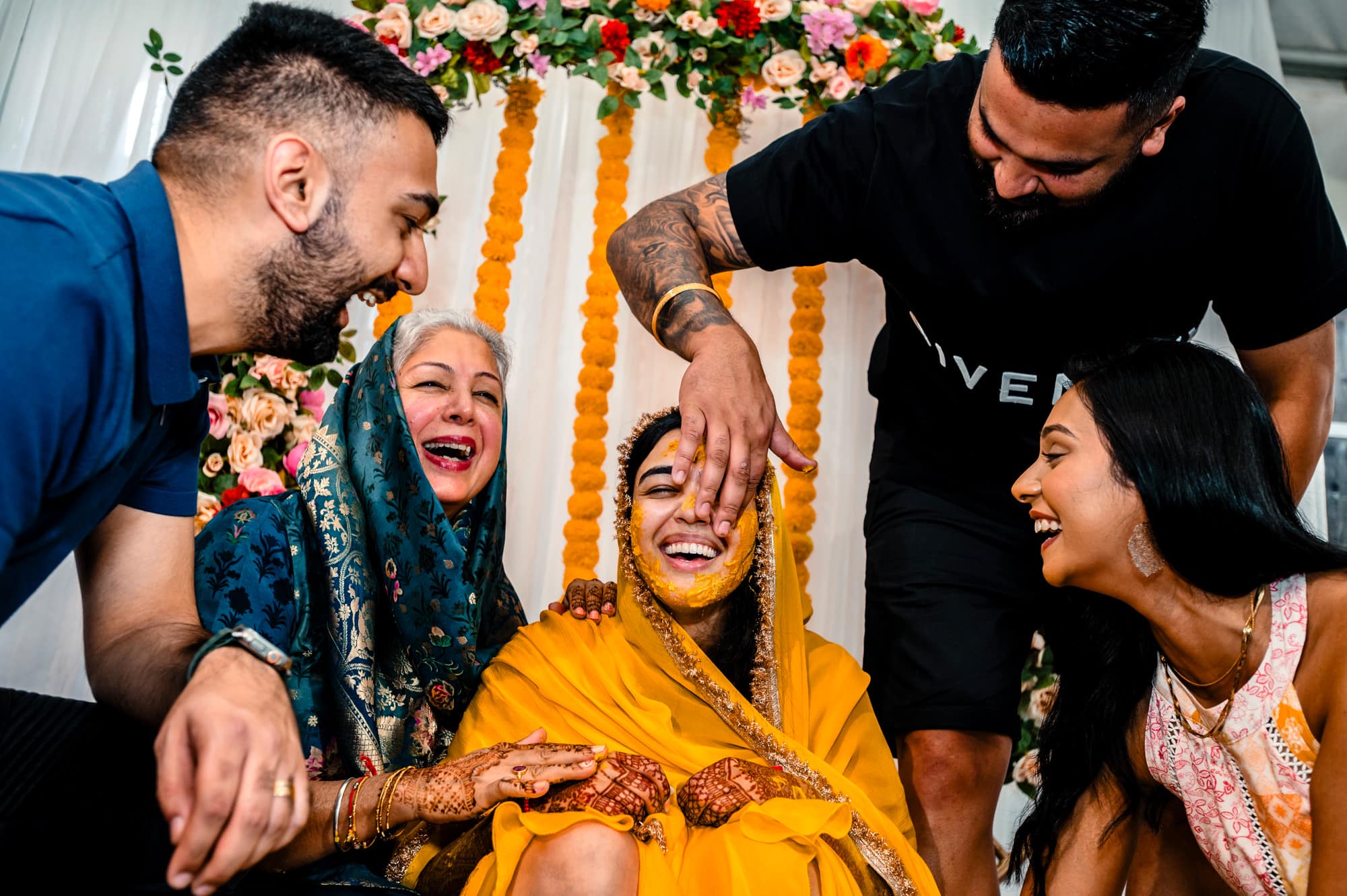 Maiyan Event with bride laughing and having haldi paste put on her face