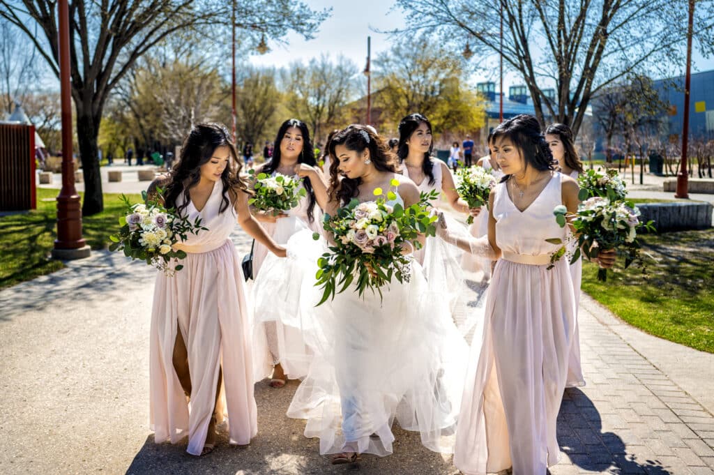 A Winnipeg bride walking with her brides maids as they help her with her wedding dress.